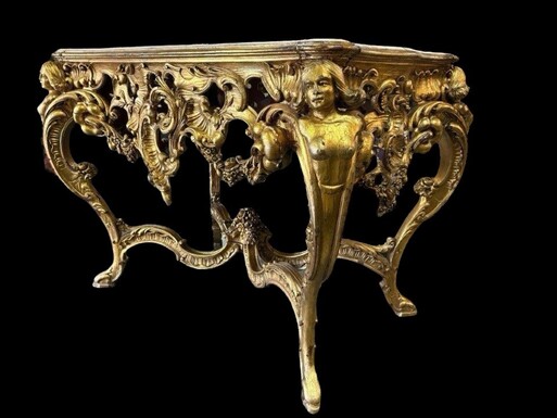 A beautiful carved and gilded center table. Decorated with openwork rocaille cartouches, palms and garlands. The falls, decorated with women in bust form, end in cambered legs joined by an x-shaped brace. Recessed pink veined white marble top, previously