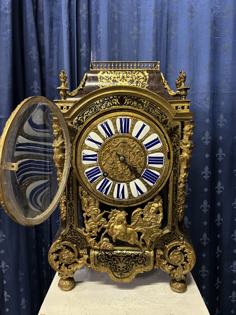 A large brass inlaid cartel on a tortoiseshell background, 18th century, Régence period. Rectangular cartel ending in scrolls decorated with gilt bronze on the front and a tripod in the centre. Gilt bronze dial with enamelled cartouches 