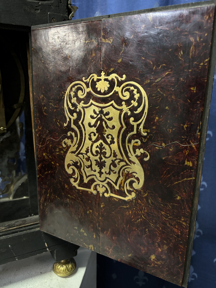 A large brass inlaid cartel on a tortoiseshell background, 18th century, Régence period. Rectangular cartel ending in scrolls decorated with gilt bronze on the front and a tripod in the centre. Gilt bronze dial with enamelled cartouches 