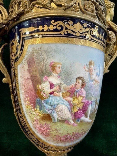 A Very Large Napoleon III Period Vase In Sevres Porcelain Decorated With A Gallant Scene On One Side And A Landscape On The Other Side, Gilded With Gold, Floral Motif And Oven Blue Background. Chased Bronze And Gilt Bronze Mount