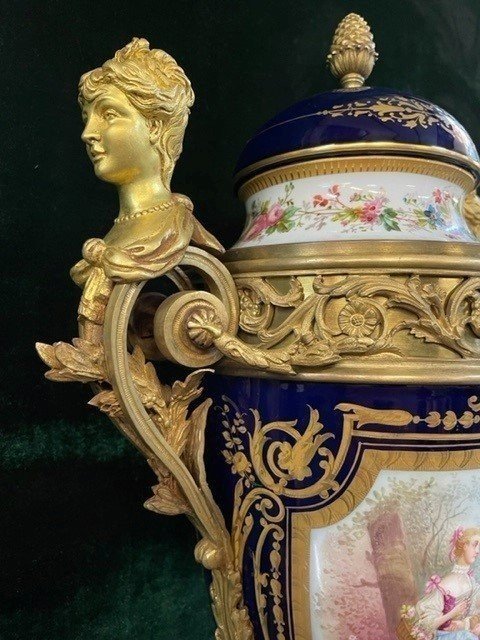 A Very Large Napoleon III Period Vase In Sevres Porcelain Decorated With A Gallant Scene On One Side And A Landscape On The Other Side, Gilded With Gold, Floral Motif And Oven Blue Background. Chased Bronze And Gilt Bronze Mount