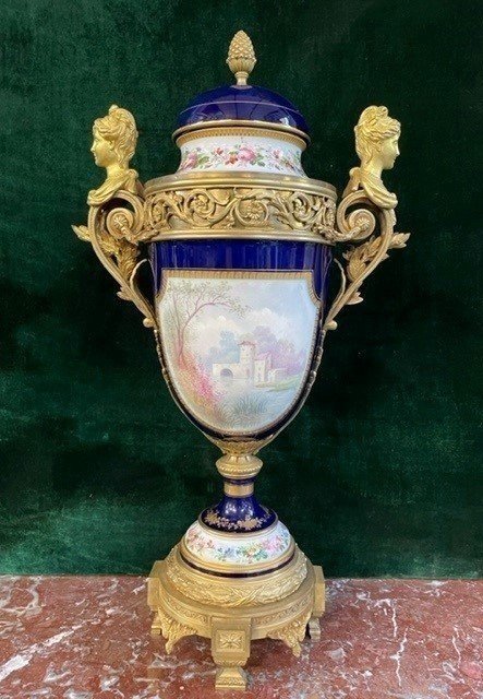 A Very Large Napoleon III Period Vase In Sevres Porcelain Decorated With A Gallant Scene On One Side And A Landscape On The Other Side, Gilded With Gold, Floral Motif And Oven Blue Background. Chased Bronze And Gilt Bronze Mount