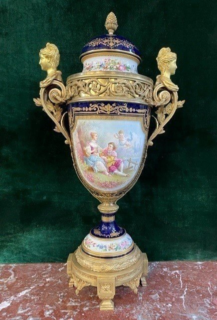 A Very Large Napoleon III Period Vase In Sevres Porcelain Decorated With A Gallant Scene On One Side And A Landscape On The Other Side, Gilded With Gold, Floral Motif And Oven Blue Background. Chased Bronze And Gilt Bronze Mount