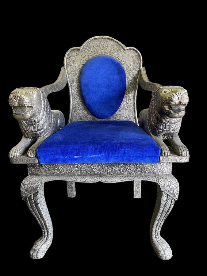 Decorative Orientalist armchair covered with tooled metal. The armchair is decorated with lions serving as armrests and is completely covered with a thin layer of silver metal decorated with flowers and ornaments and colourful fabric