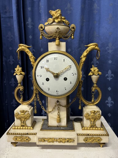 Elegant Louis XVI style clock from the 18th century. Beautiful 18th century marble and gilt bronze mantel clock decorated with vases of flowers, ornaments, griffin heads and bronze girlandes. The pendulum and key are present. 18thC.