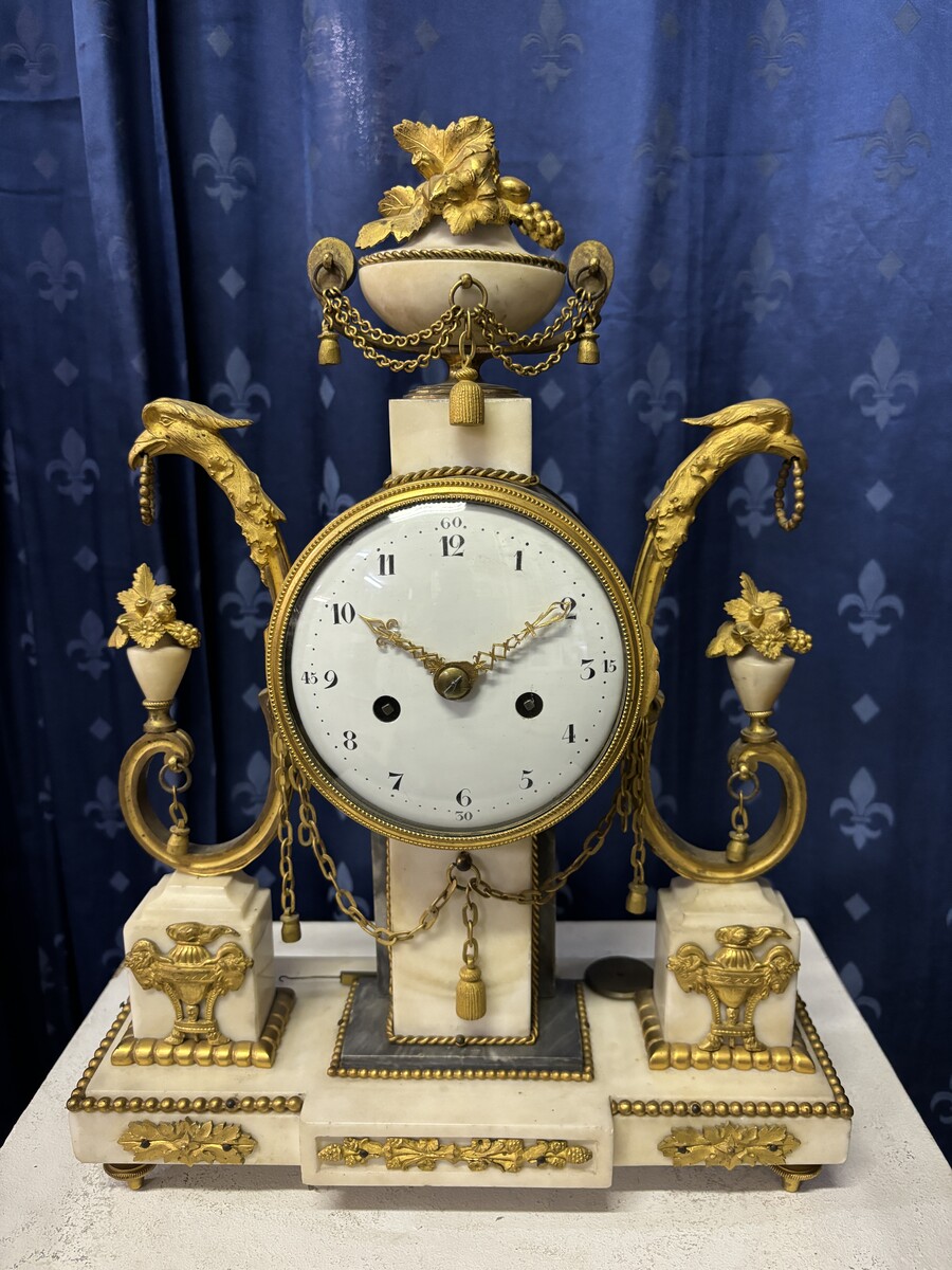 Elegant Louis XVI style clock from the 18th century. Beautiful 18th century marble and gilt bronze mantel clock decorated with vases of flowers, ornaments, griffin heads and bronze girlandes. The pendulum and key are present. 18thC.