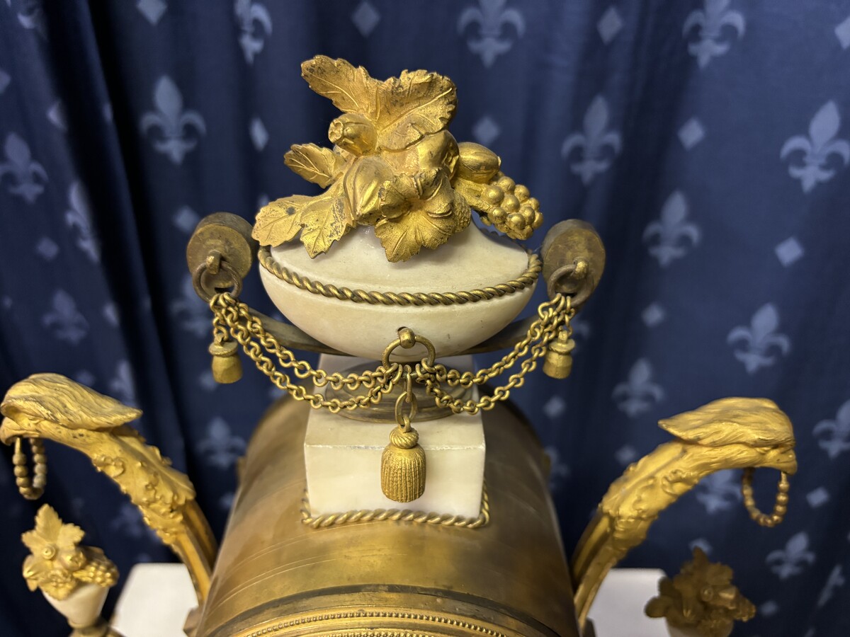 Elegant Louis XVI style clock from the 18th century. Beautiful 18th century marble and gilt bronze mantel clock decorated with vases of flowers, ornaments, griffin heads and bronze girlandes. The pendulum and key are present. 18thC.