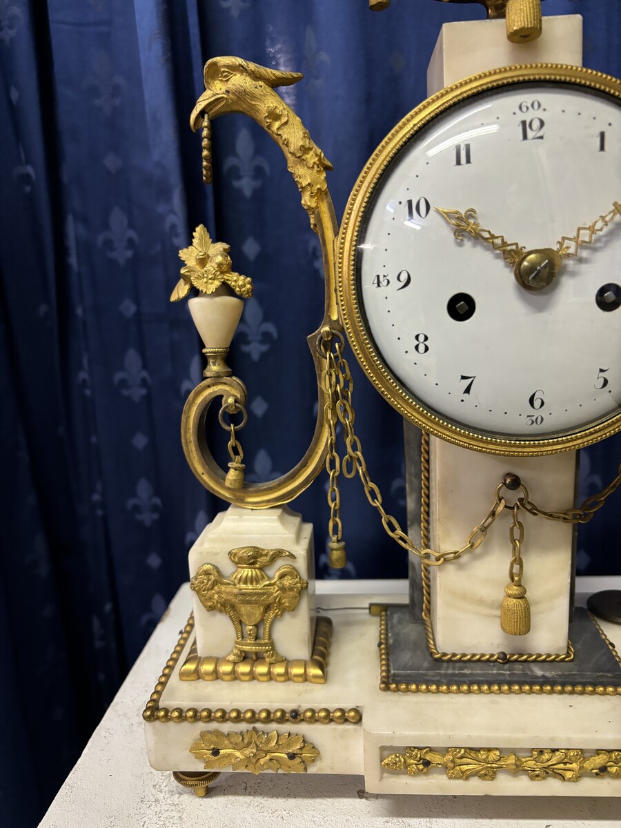 Elegant Louis XVI style clock from the 18th century. Beautiful 18th century marble and gilt bronze mantel clock decorated with vases of flowers, ornaments, griffin heads and bronze girlandes. The pendulum and key are present. 18thC.