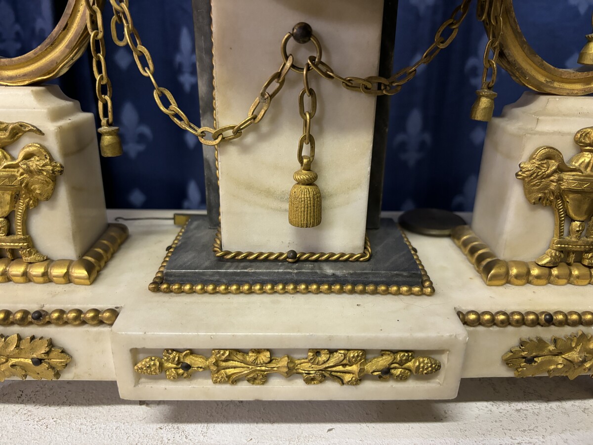 Elegant Louis XVI style clock from the 18th century. Beautiful 18th century marble and gilt bronze mantel clock decorated with vases of flowers, ornaments, griffin heads and bronze girlandes. The pendulum and key are present. 18thC.