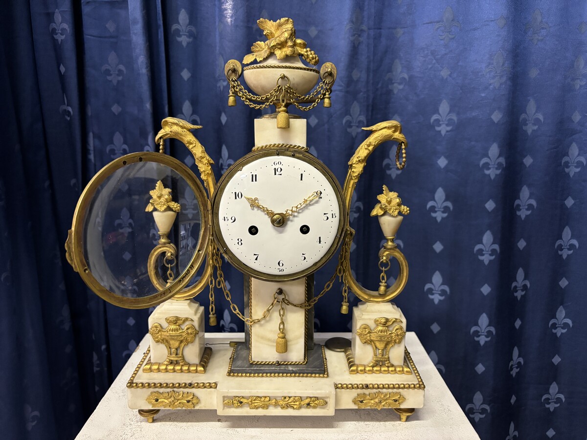 Elegant Louis XVI style clock from the 18th century. Beautiful 18th century marble and gilt bronze mantel clock decorated with vases of flowers, ornaments, griffin heads and bronze girlandes. The pendulum and key are present. 18thC.