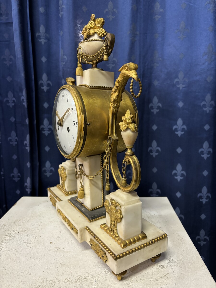 Elegant Louis XVI style clock from the 18th century. Beautiful 18th century marble and gilt bronze mantel clock decorated with vases of flowers, ornaments, griffin heads and bronze girlandes. The pendulum and key are present. 18thC.