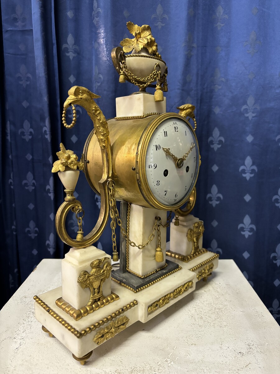 Elegant Louis XVI style clock from the 18th century. Beautiful 18th century marble and gilt bronze mantel clock decorated with vases of flowers, ornaments, griffin heads and bronze girlandes. The pendulum and key are present. 18thC.