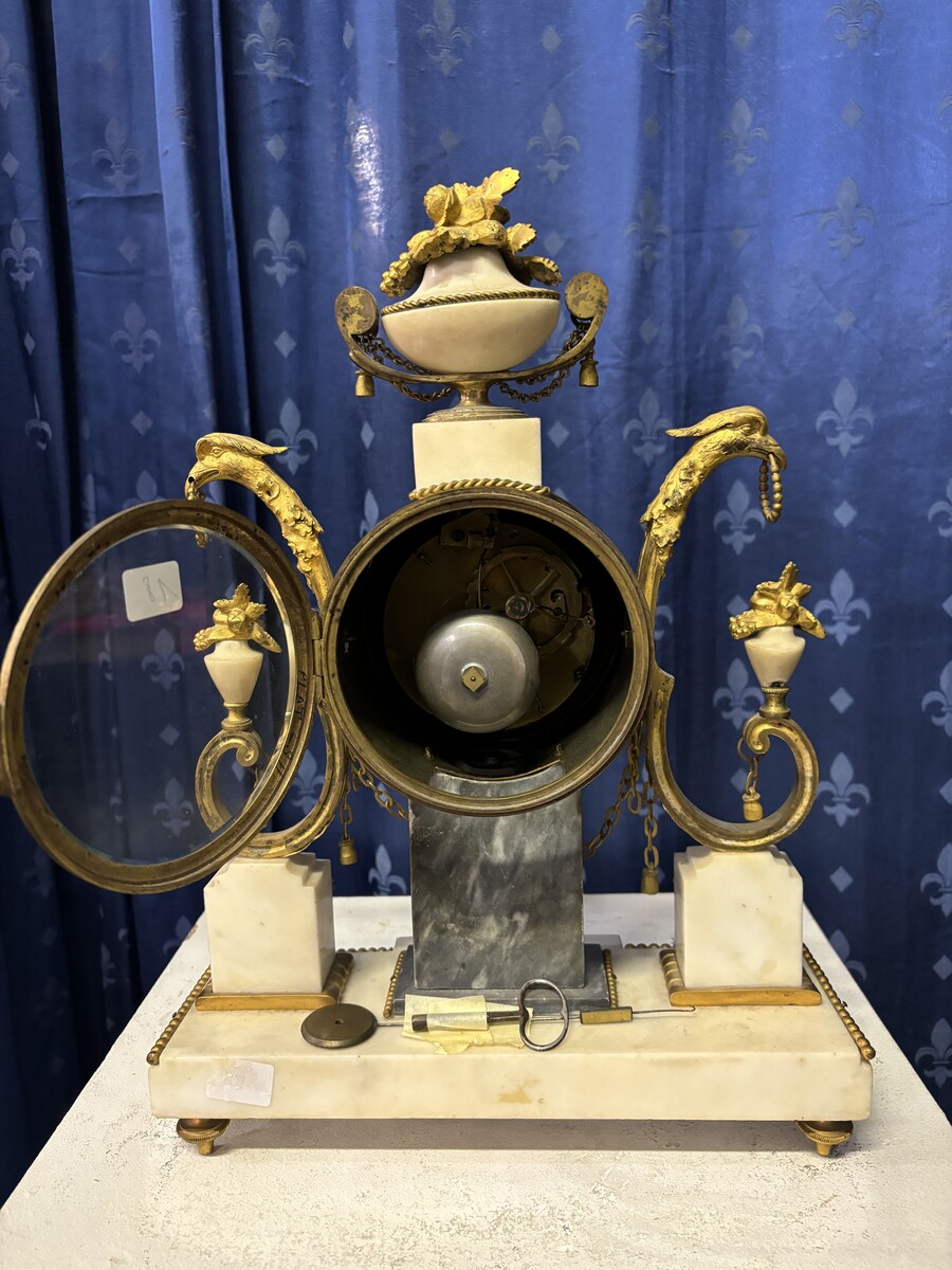 Elegant Louis XVI style clock from the 18th century. Beautiful 18th century marble and gilt bronze mantel clock decorated with vases of flowers, ornaments, griffin heads and bronze girlandes. The pendulum and key are present. 18thC.