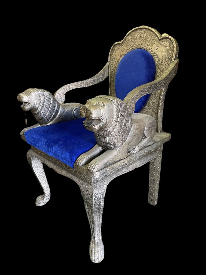 Highly decorative Orientalist armchair covered with tooled metal. The armchair is decorated with lions serving as armrests and is completely covered with a thin layer of silver metal decorated with flowers and ornaments and colourful fabric