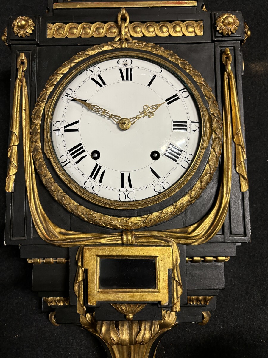 Large 18th century Louis XVI style wooden wall clock ( 78 cm ). Decorative cartel in black and gilded wood with the following dimensions: Height : 78 cm Width : 35 cm Depth : 18 cm. 18th century cartel in good condition with original clock.