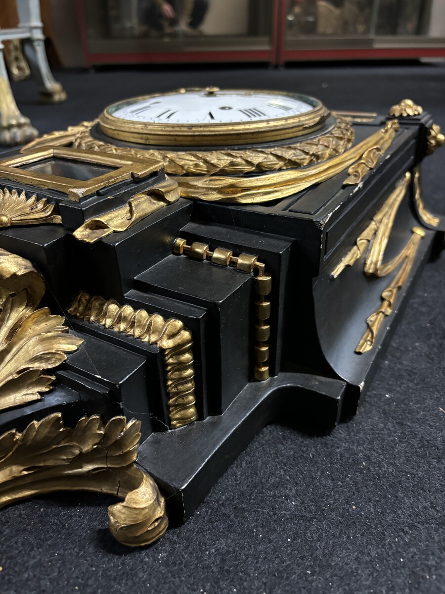 Large 18th century Louis XVI style wooden wall clock ( 78 cm ). Decorative cartel in black and gilded wood with the following dimensions: Height : 78 cm Width : 35 cm Depth : 18 cm. 18th century cartel in good condition with original clock.