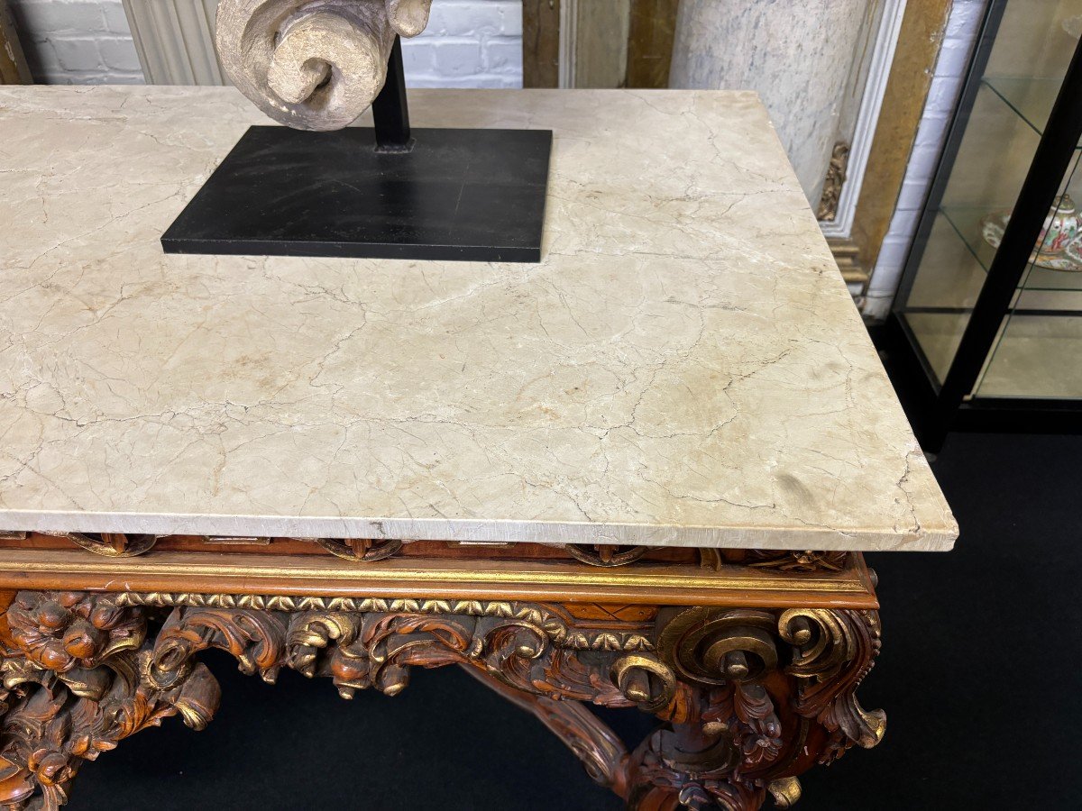 Large decorative console in carved wood 20th century. Beautiful console in wood with gilt accents and on top a top in travertine Dimensions : Width : 170 cm Height : 90 cm Depth : 71 cm In very good condition