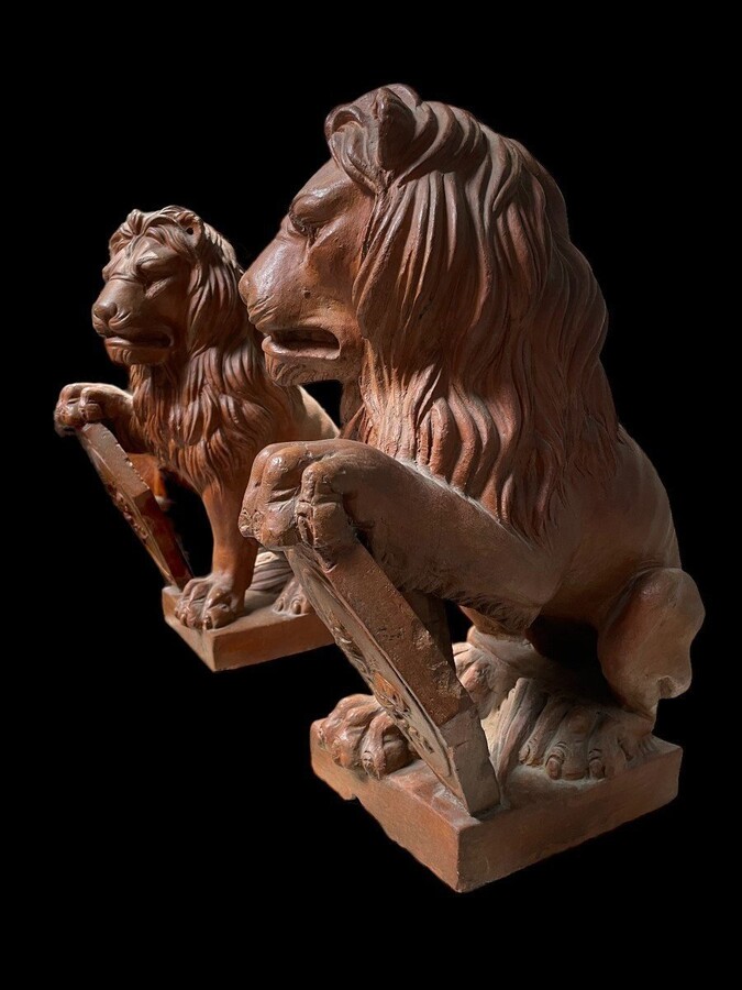 Pair of decorative lions with shields in terra cotta Beautiful pair of lions from Florence Italy from around 1900-1920. Both in good condition with some minor defects.