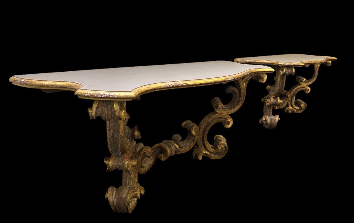 Pair of large consoles in gilt wood , Italian 18th century. Very decorative consoles decorated with large scrolls/ornaments in gilt wood with a painted top (tops in wood are recent , edge of table from the time). Dimensions : Width : 191 cm Height : 83,5