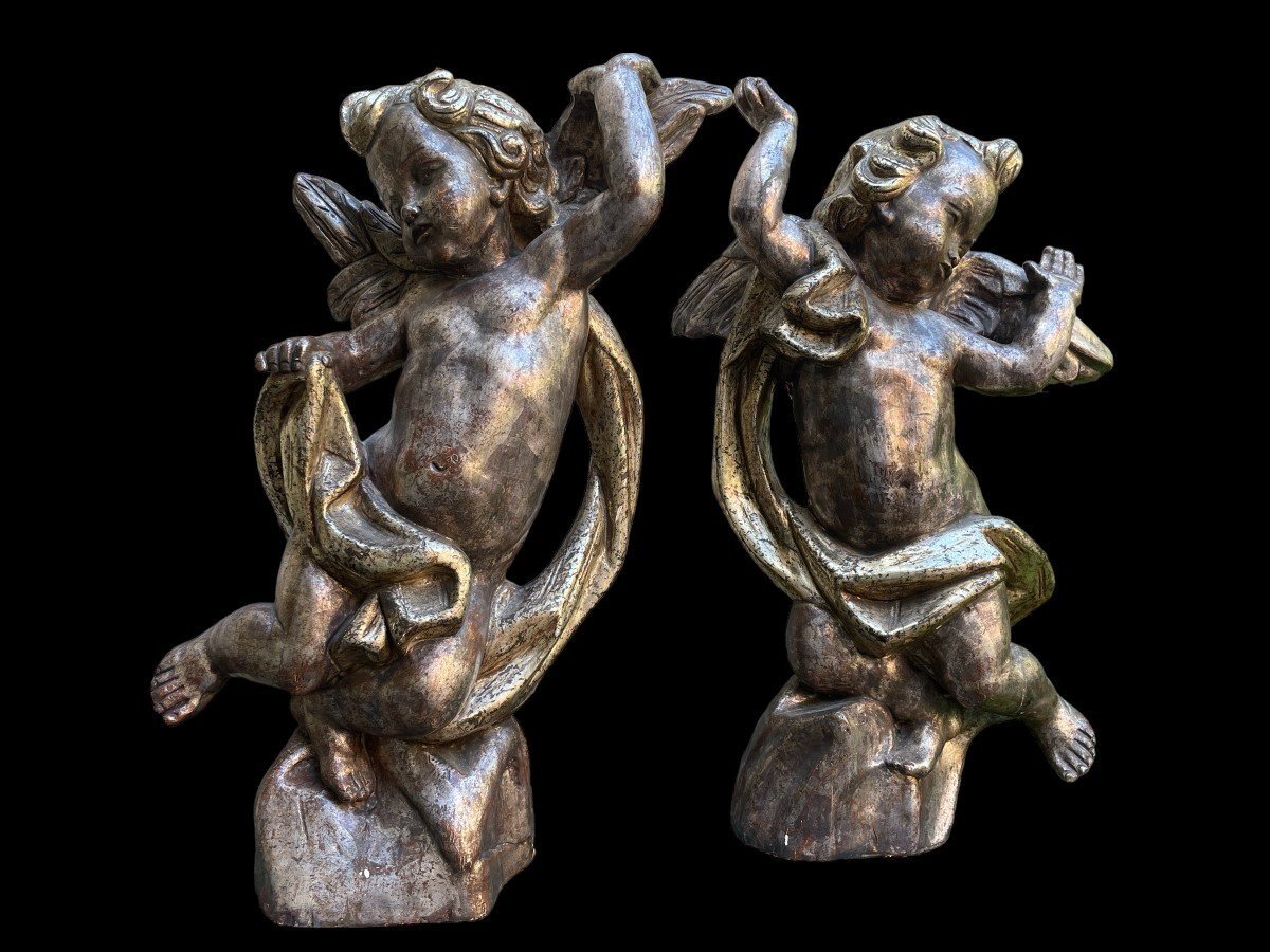 Pair of large silver/golden wood angels circa 1900. Decorative wooden angels in good condition. Dimensions: Height: 81 and 84 cm Width : 47 and 54 cm Depth : 24 and 25 cm Sculptures from Italy circa 1900