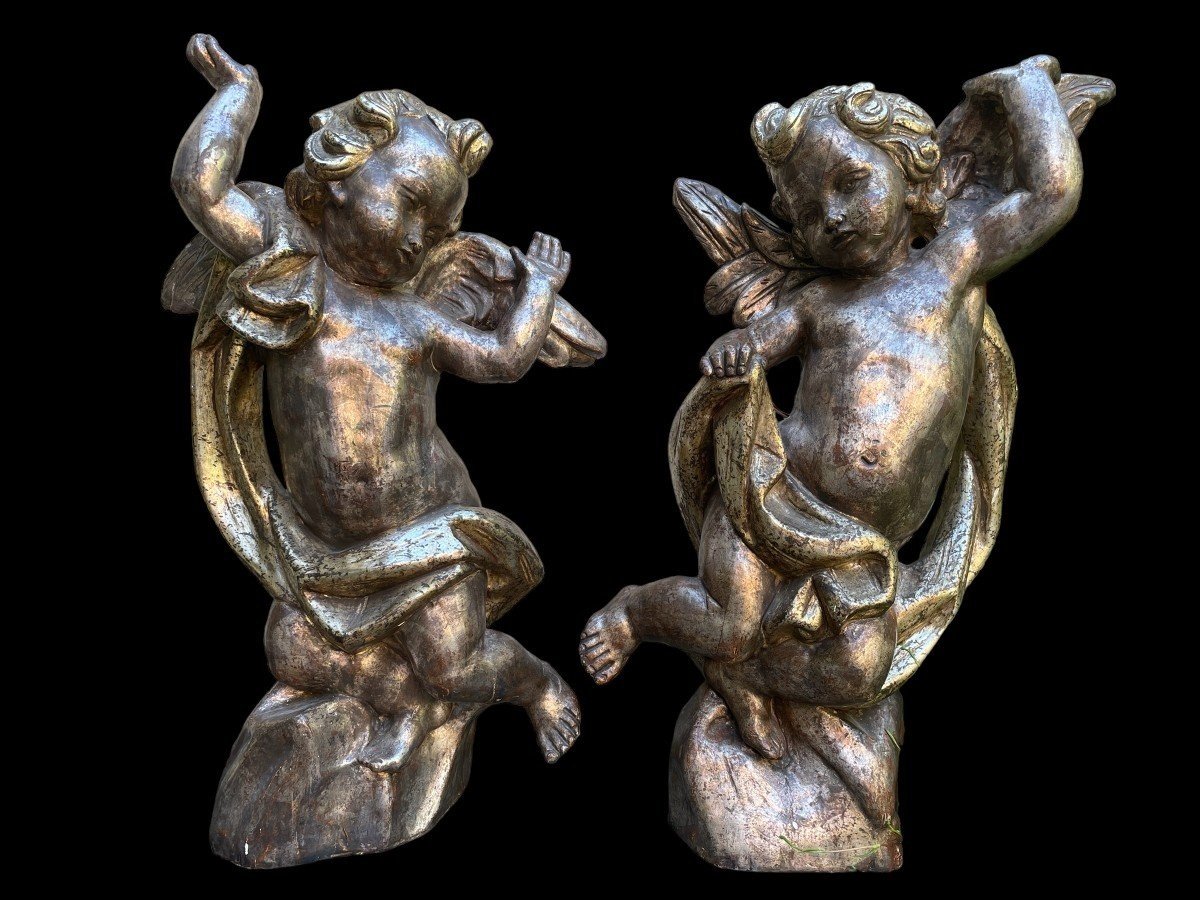 Pair of large silver/golden wood angels circa 1900. Decorative wooden angels in good condition. Dimensions: Height: 81 and 84 cm Width : 47 and 54 cm Depth : 24 and 25 cm Sculptures from Italy circa 1900