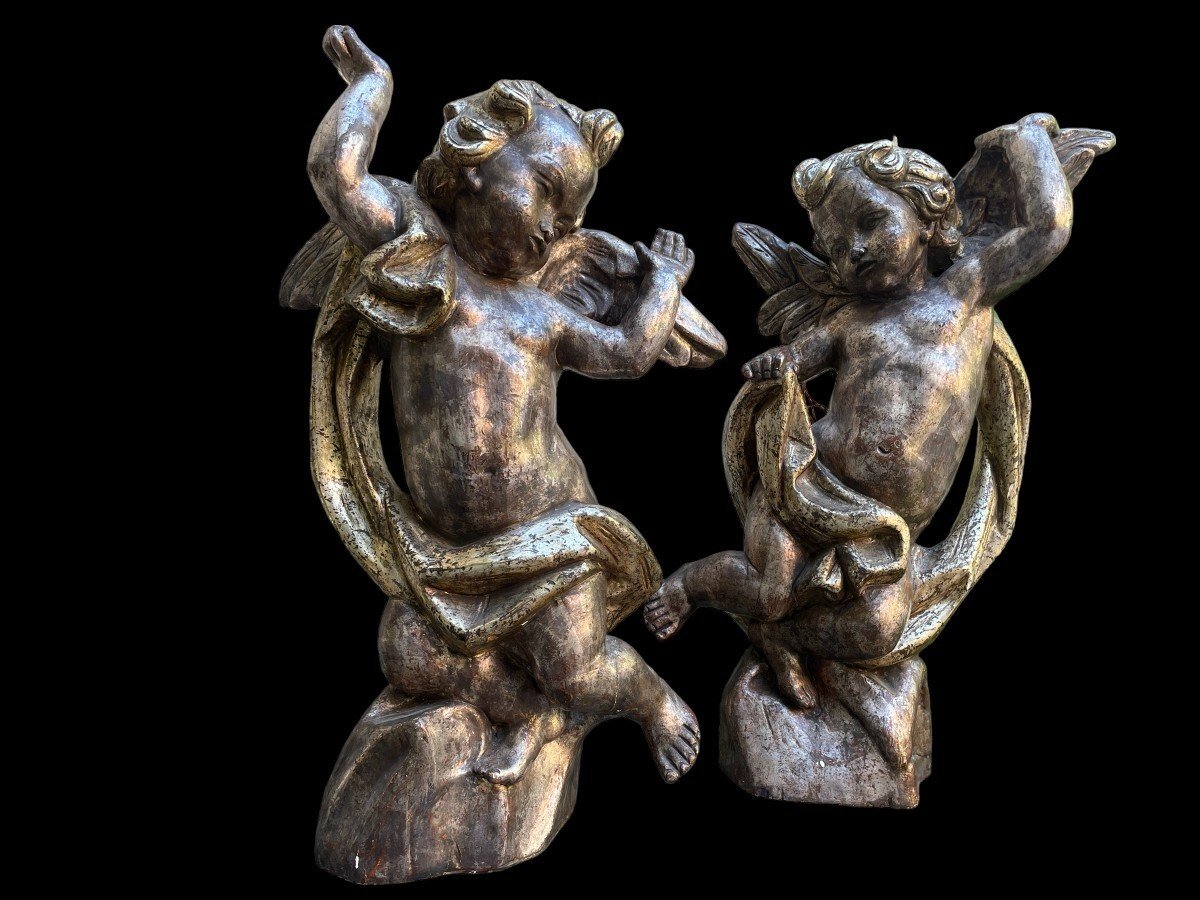 Pair of large silver/golden wood angels circa 1900. Decorative wooden angels in good condition. Dimensions: Height: 81 and 84 cm Width : 47 and 54 cm Depth : 24 and 25 cm Sculptures from Italy circa 1900