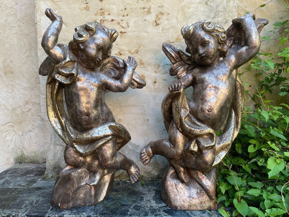 Pair of large silver/golden wood angels circa 1900. Decorative wooden angels in good condition. Dimensions: Height: 81 and 84 cm Width : 47 and 54 cm Depth : 24 and 25 cm Sculptures from Italy circa 1900