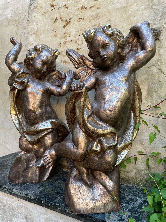 Pair of large silver/golden wood angels circa 1900. Decorative wooden angels in good condition. Dimensions: Height: 81 and 84 cm Width : 47 and 54 cm Depth : 24 and 25 cm Sculptures from Italy circa 1900