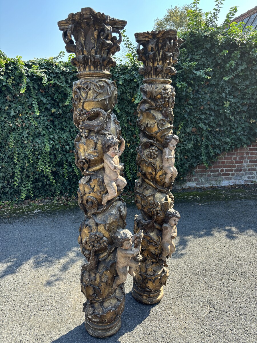 Pair of large turned columns with capitals 17th century. Very decorative polychrome oak columns from the Baroque period decorated with grapevines , birds, per column 2 putti and on top a corinthian capital The columns have some missing parts