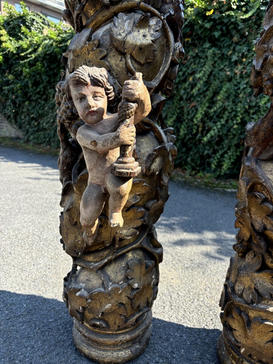 Pair of large turned columns with capitals 17th century. Very decorative polychrome oak columns from the Baroque period decorated with grapevines , birds, per column 2 putti and on top a corinthian capital The columns have some missing parts