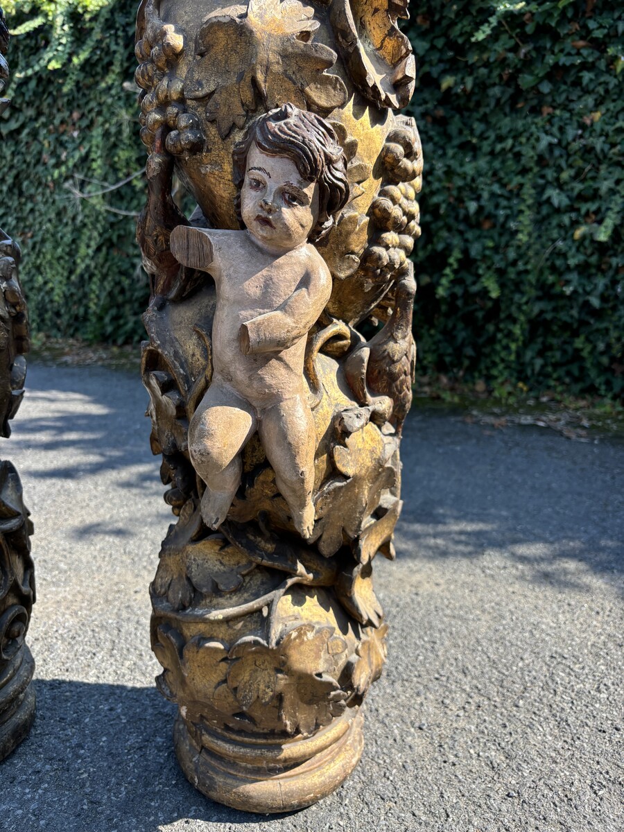 Pair of large turned columns with capitals 17th century. Very decorative polychrome oak columns from the Baroque period decorated with grapevines , birds, per column 2 putti and on top a corinthian capital The columns have some missing parts