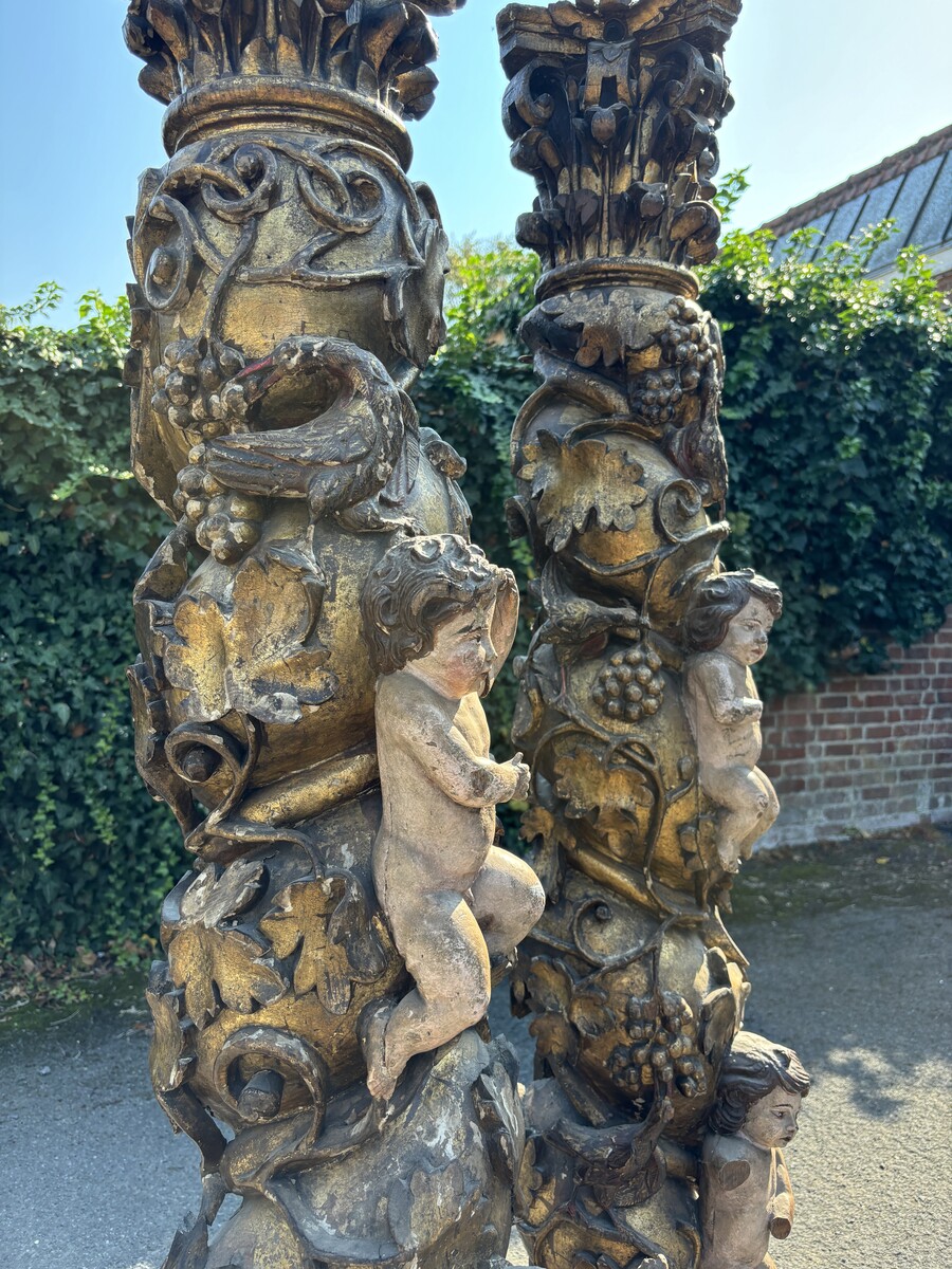 Pair of large turned columns with capitals 17th century. Very decorative polychrome oak columns from the Baroque period decorated with grapevines , birds, per column 2 putti and on top a corinthian capital The columns have some missing parts