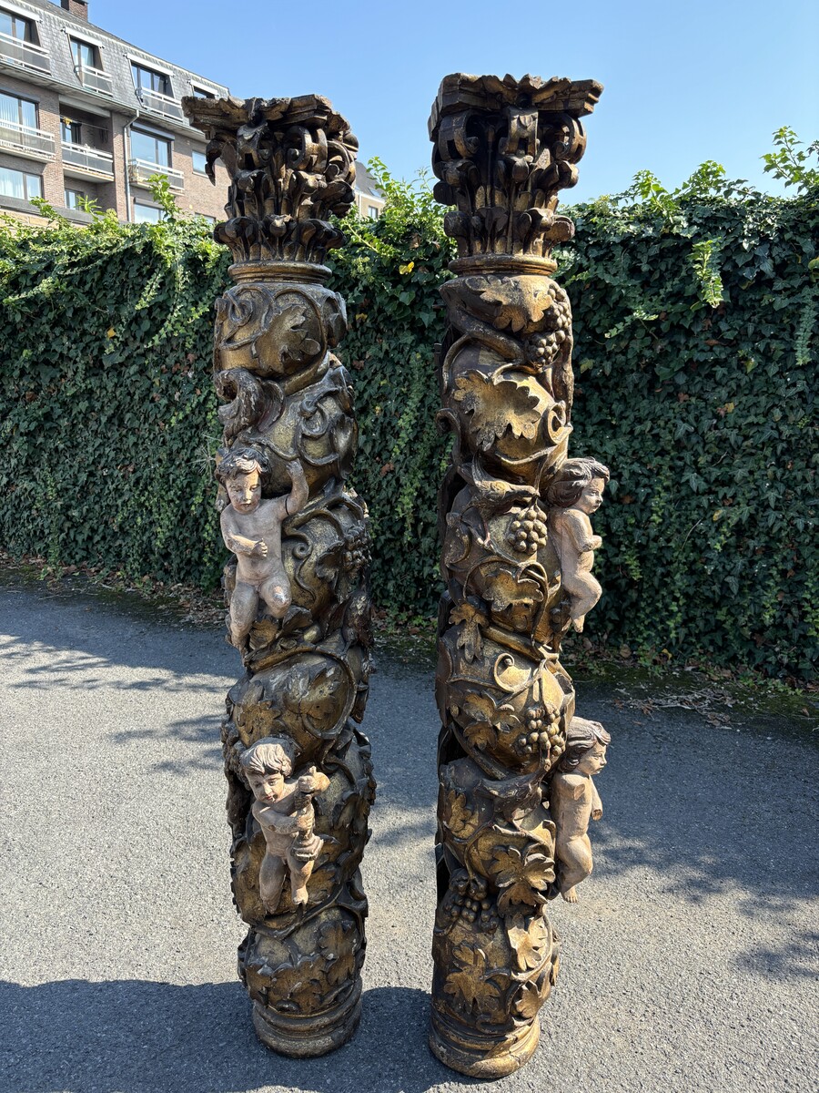 Pair of large turned columns with capitals 17th century. Very decorative polychrome oak columns from the Baroque period decorated with grapevines , birds, per column 2 putti and on top a corinthian capital The columns have some missing parts