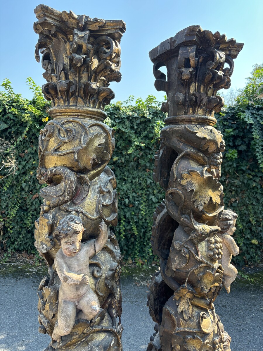 Pair of large turned columns with capitals 17th century. Very decorative polychrome oak columns from the Baroque period decorated with grapevines , birds, per column 2 putti and on top a corinthian capital The columns have some missing parts