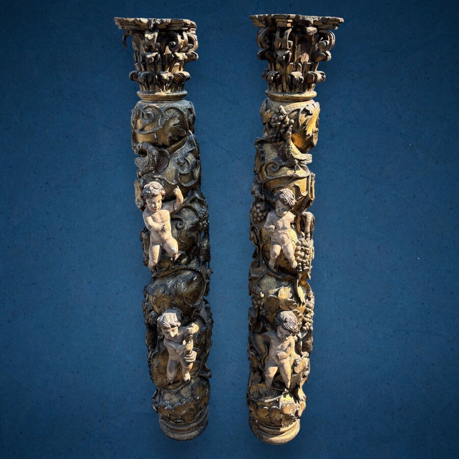 Pair of large turned columns with capitals 17th century. Very decorative polychrome oak columns from the Baroque period decorated with grapevines , birds, per column 2 putti and on top a corinthian capital The columns have some missing parts