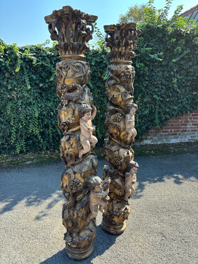  Pair of large turned columns with capitals 17th century. Very decorative polychrome oak columns from the Baroque period decorated with grapevines , birds, per column 2 putti and on top a corinthian capital The columns have some missing parts