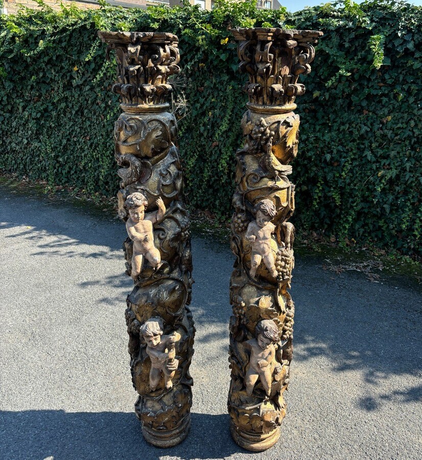  Pair of large turned columns with capitals 17th century. Very decorative polychrome oak columns from the Baroque period decorated with grapevines , birds, per column 2 putti and on top a corinthian capital The columns have some missing parts