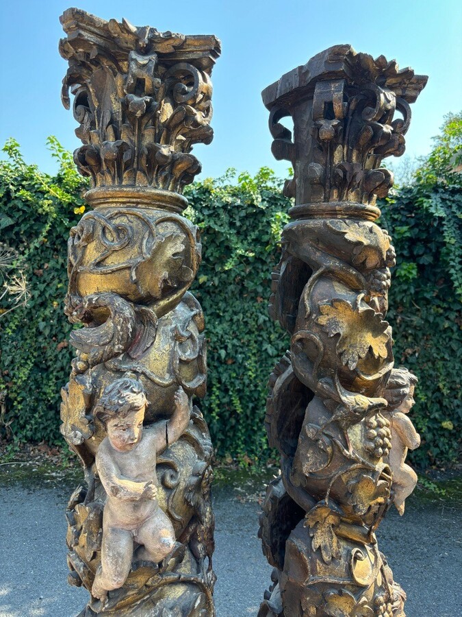  Pair of large turned columns with capitals 17th century. Very decorative polychrome oak columns from the Baroque period decorated with grapevines , birds, per column 2 putti and on top a corinthian capital The columns have some missing parts