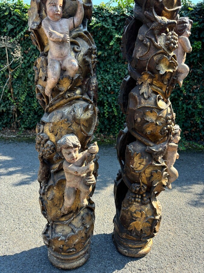  Pair of large turned columns with capitals 17th century. Very decorative polychrome oak columns from the Baroque period decorated with grapevines , birds, per column 2 putti and on top a corinthian capital The columns have some missing parts