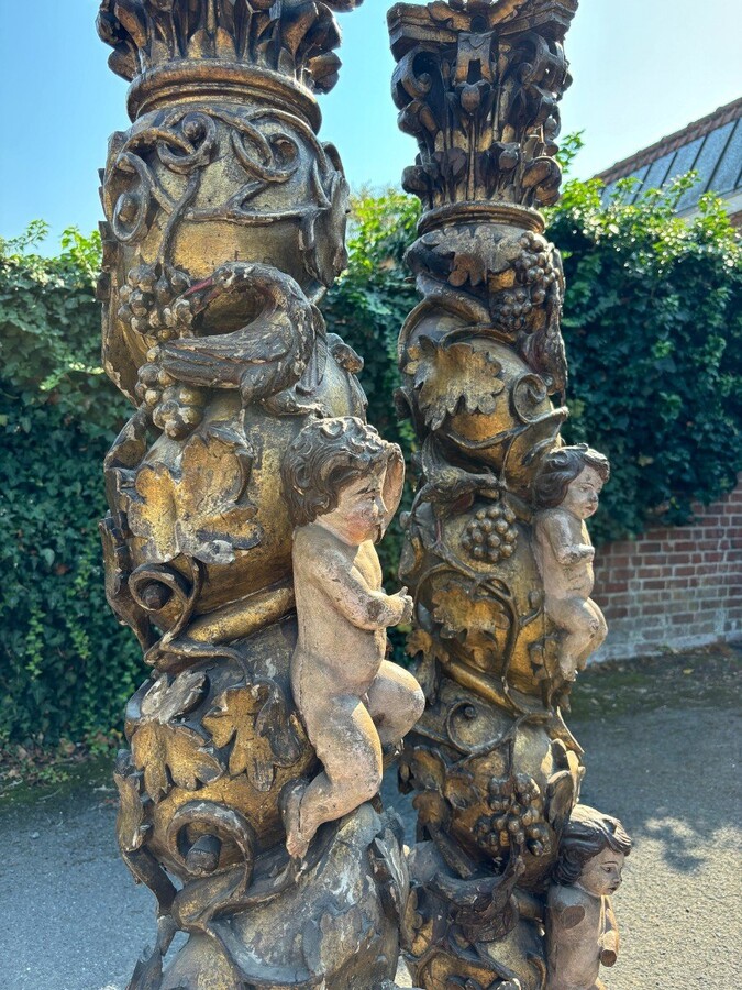  Pair of large turned columns with capitals 17th century. Very decorative polychrome oak columns from the Baroque period decorated with grapevines , birds, per column 2 putti and on top a corinthian capital The columns have some missing parts