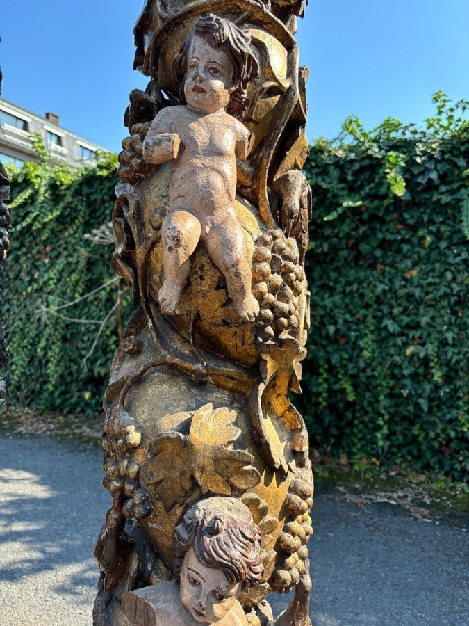  Pair of large turned columns with capitals 17th century. Very decorative polychrome oak columns from the Baroque period decorated with grapevines , birds, per column 2 putti and on top a corinthian capital The columns have some missing parts