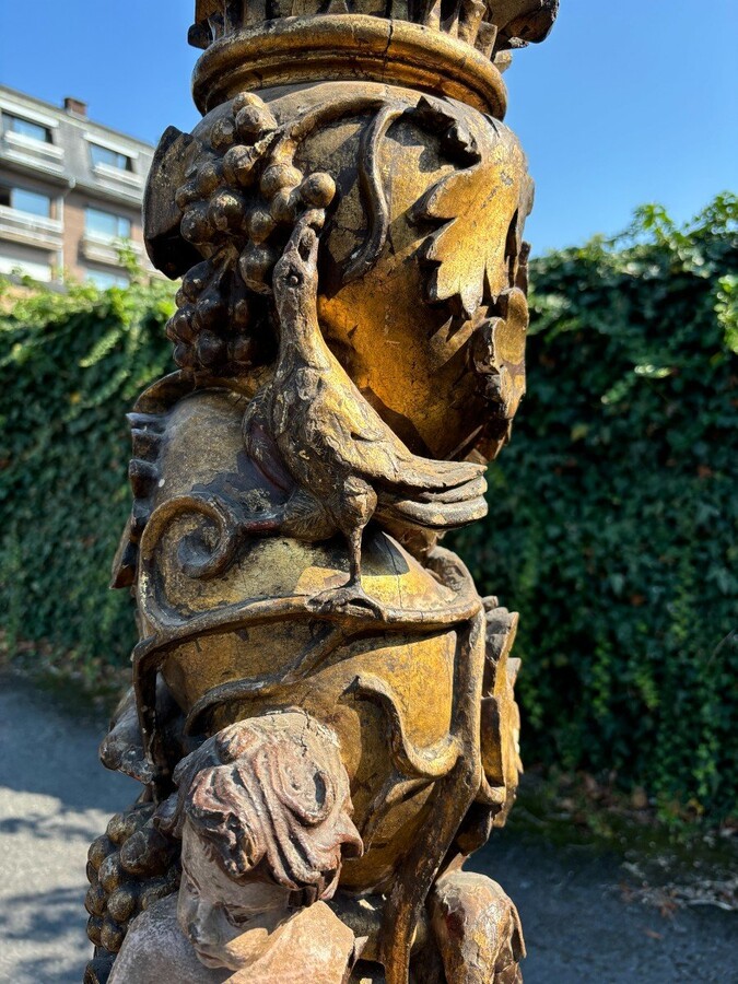  Pair of large turned columns with capitals 17th century. Very decorative polychrome oak columns from the Baroque period decorated with grapevines , birds, per column 2 putti and on top a corinthian capital The columns have some missing parts