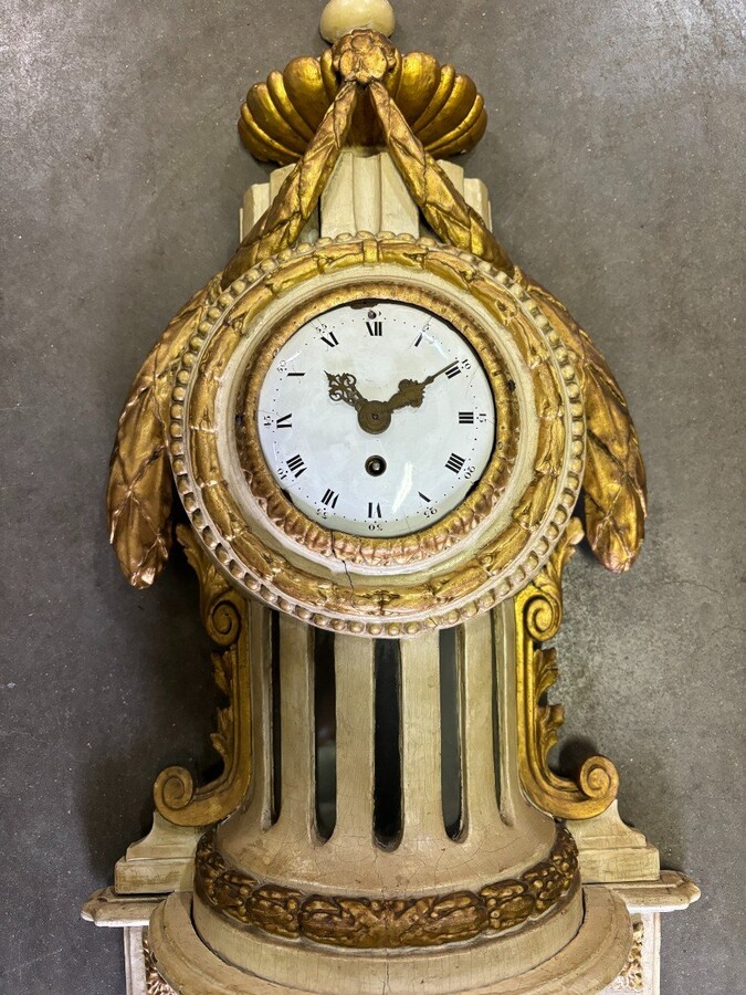 Wall clock on Louis XVI base in painted wood 18th century Decorative cartel in an 18th century wooden case + original dial and wooden base, 19th century movement. Dimensions : Total height: 84 cm Cartel: 56 cm , base: 28 cm Width : 36 cm Depth : 12 cm