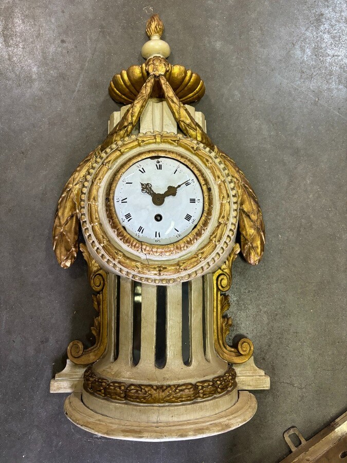 Wall clock on Louis XVI base in painted wood 18th century Decorative cartel in an 18th century wooden case + original dial and wooden base, 19th century movement. Dimensions : Total height: 84 cm Cartel: 56 cm , base: 28 cm Width : 36 cm Depth : 12 cm