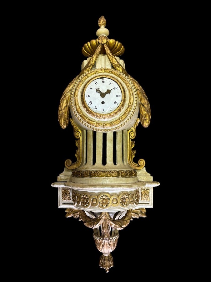 Wall clock on Louis XVI base in painted wood 18th century Decorative cartel in an 18th century wooden case + original dial and wooden base, 19th century movement. Dimensions : Total height: 84 cm Cartel: 56 cm , base: 28 cm Width : 36 cm Depth : 12 cm